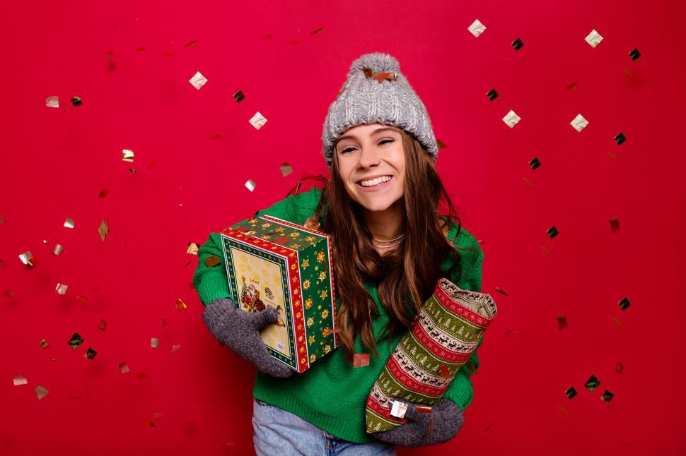 Free Image of Attractive young lady wearing winter outfit holding holiday gift 