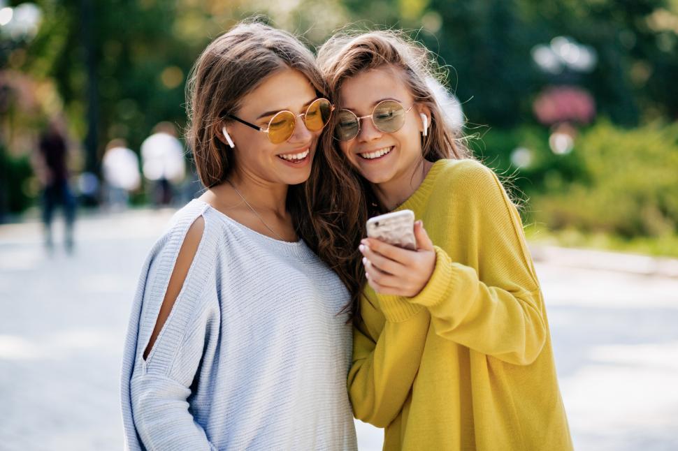 Free Image of Two funny smiling sisters making selfie on smartphone 