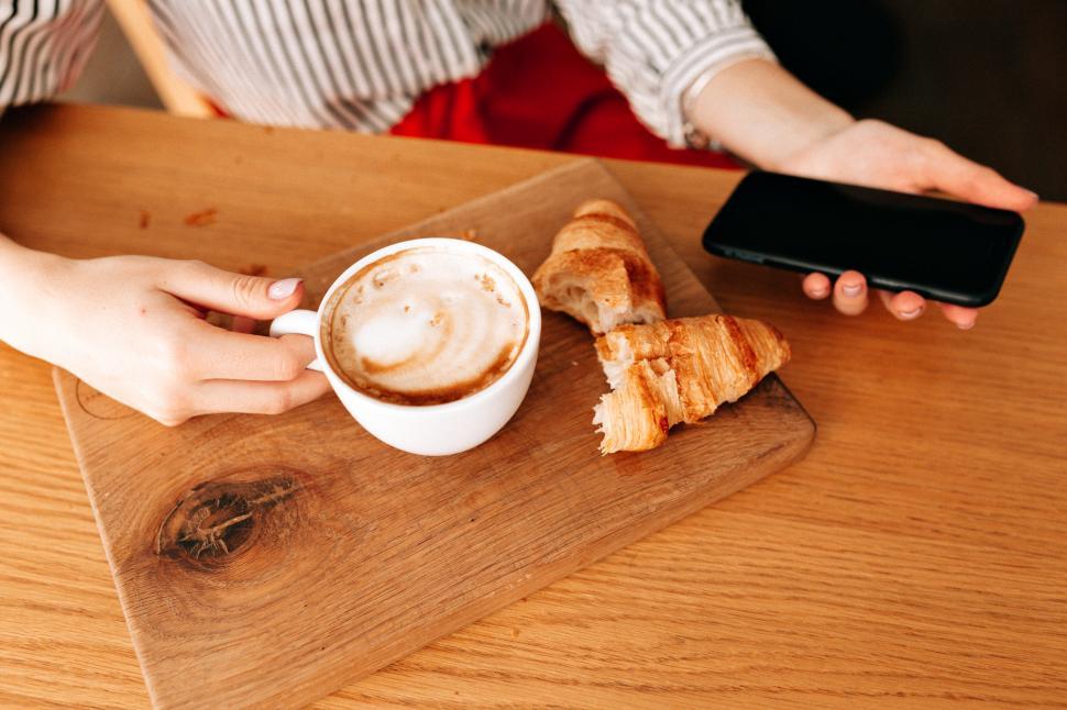 Free Image of Crop photo of cup with coffee and french croissants on the table 