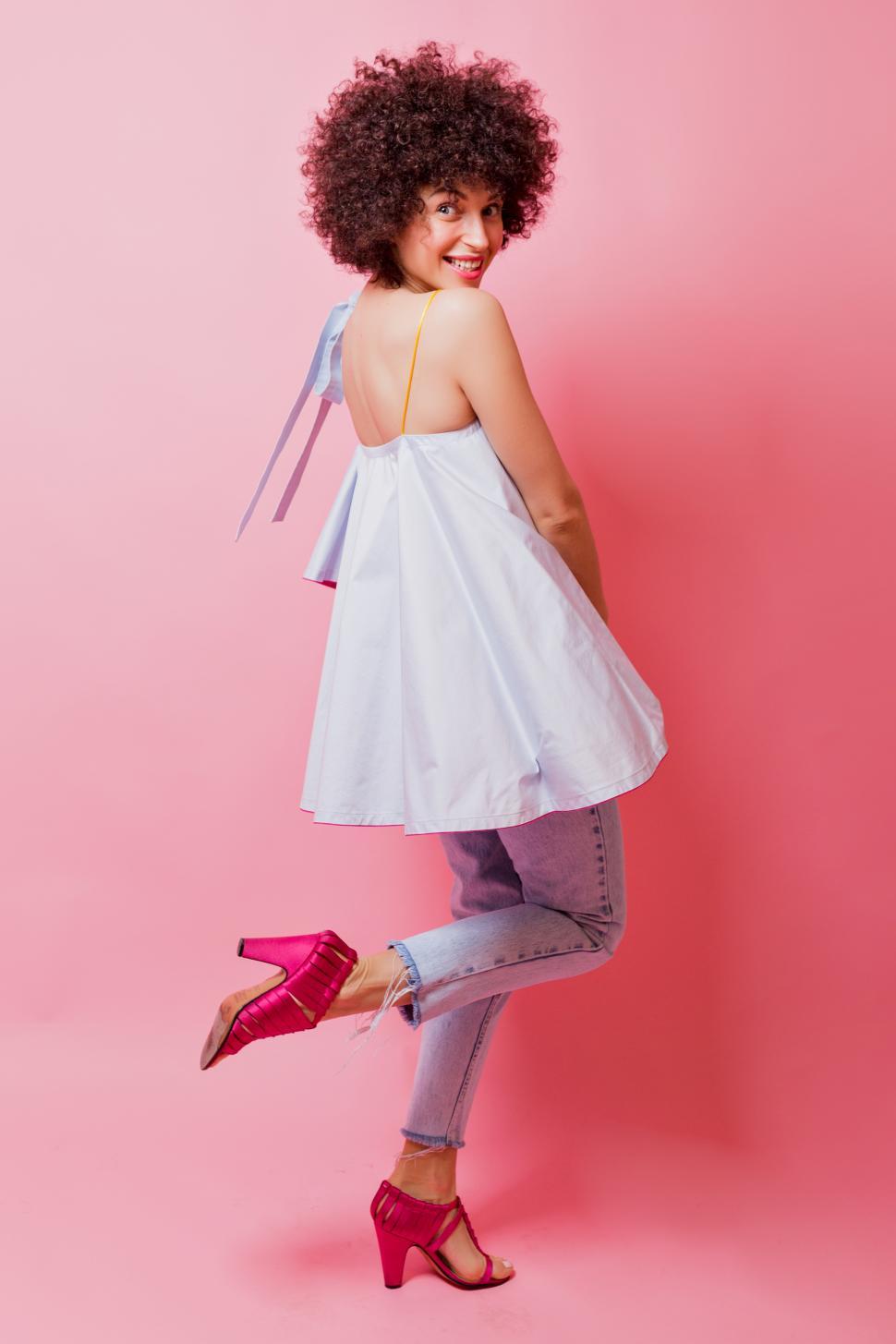 Free Image of Woman with short curly hair dressed blue shirt, jeans and pink heels 