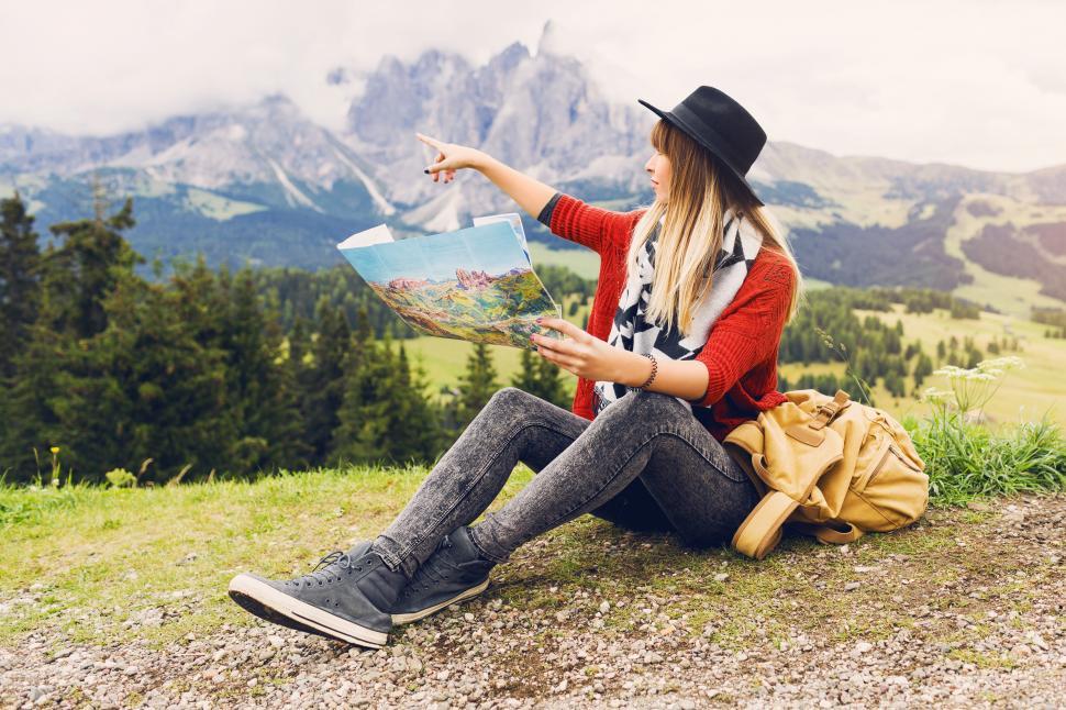 Free Image of Traveler young woman with backpack and hat sitting on grass 
