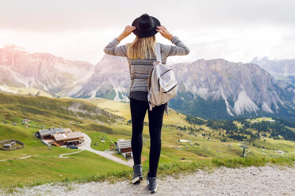Free Image of Woman traveler with backpack holding hat and looking forward 
