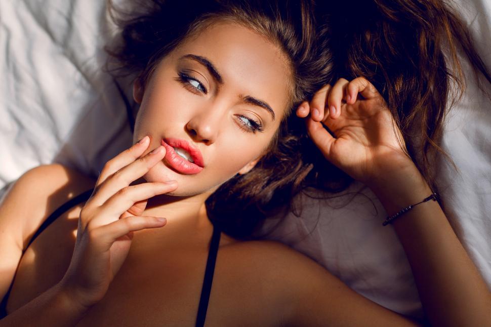 Free Image of Young woman with amazing blue eyes and full lips lying on pillow in her bedroom. 