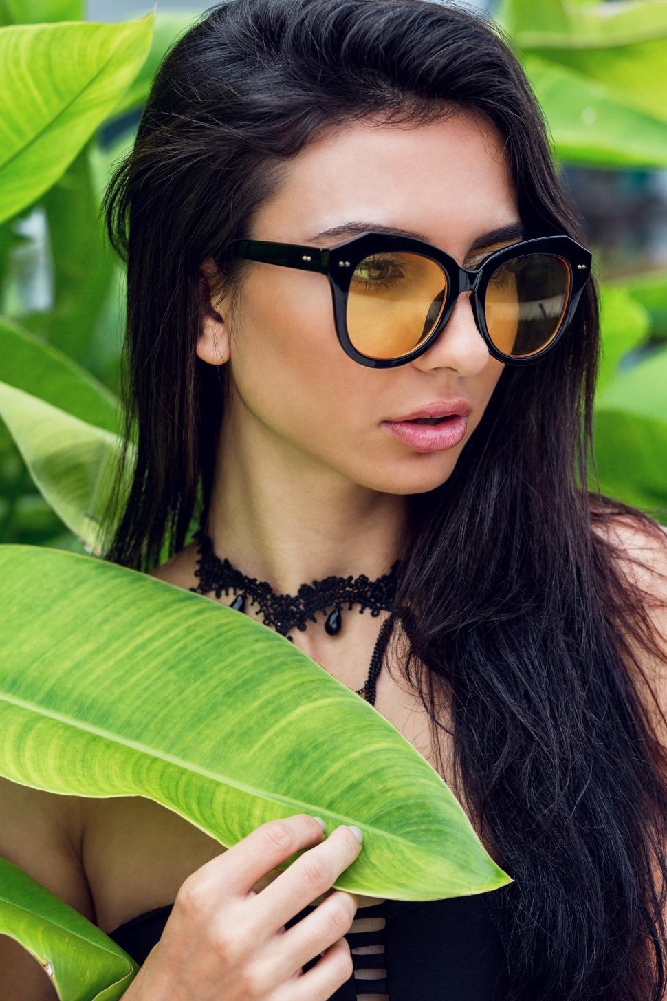 Free Image of Woman in trendy necklace , black swimwear and trendy yellow sunglasses 