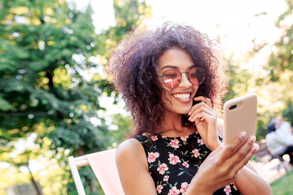 Free Image of Smiling black woman using mobile phone and making self portrait 