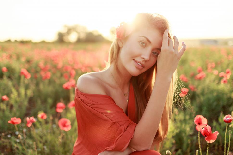 Free Image of Smiling young long-haired woman  walking in poppy field in the evening. 