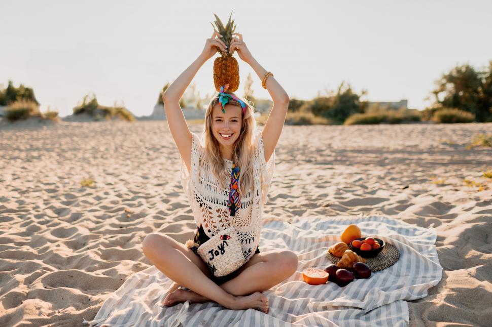 Free Image of Summertime picture of lovely blond woman holding pineapple on her head 