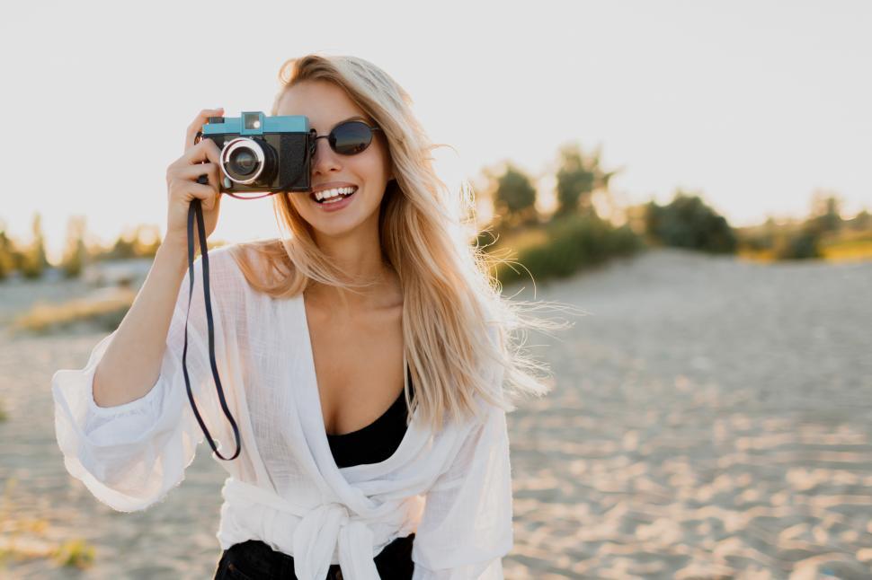Free Image of Stylish girl with retro camera on sunny beach. 