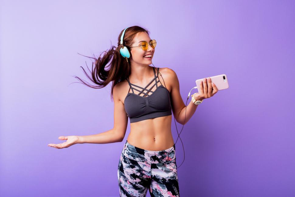 Free Image of Sporty woman in athleisure gear against purple wall 
