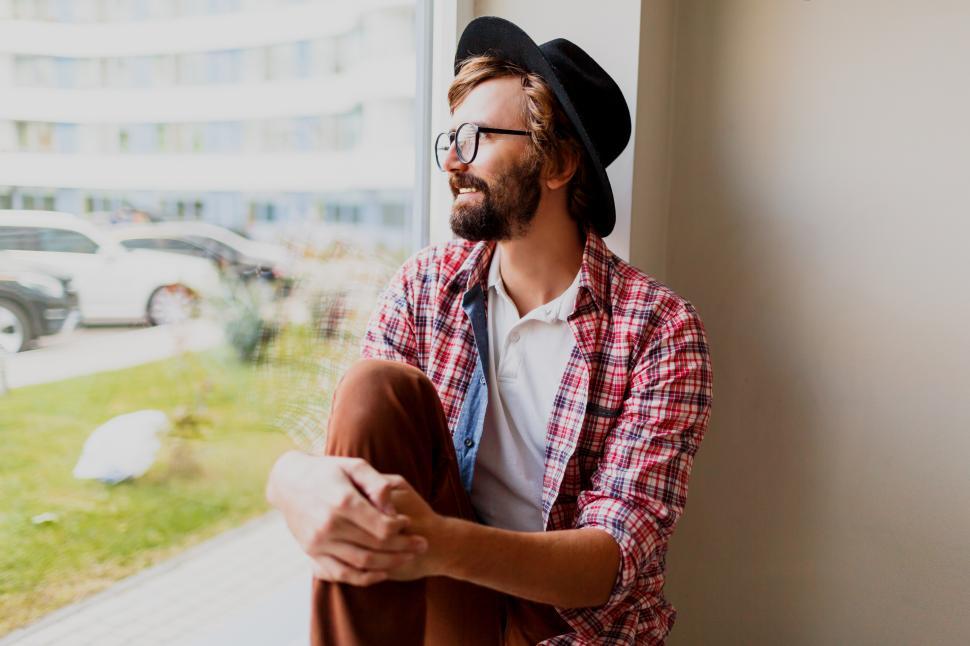 Free Image of Pensive man with beard in stylish glasses and spring outfit relaxing during work day 