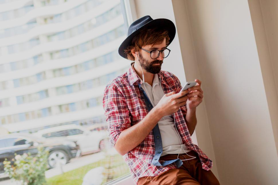 Free Image of Man with beard in sunglasses texting messages via smartphone and blogging in social networks 