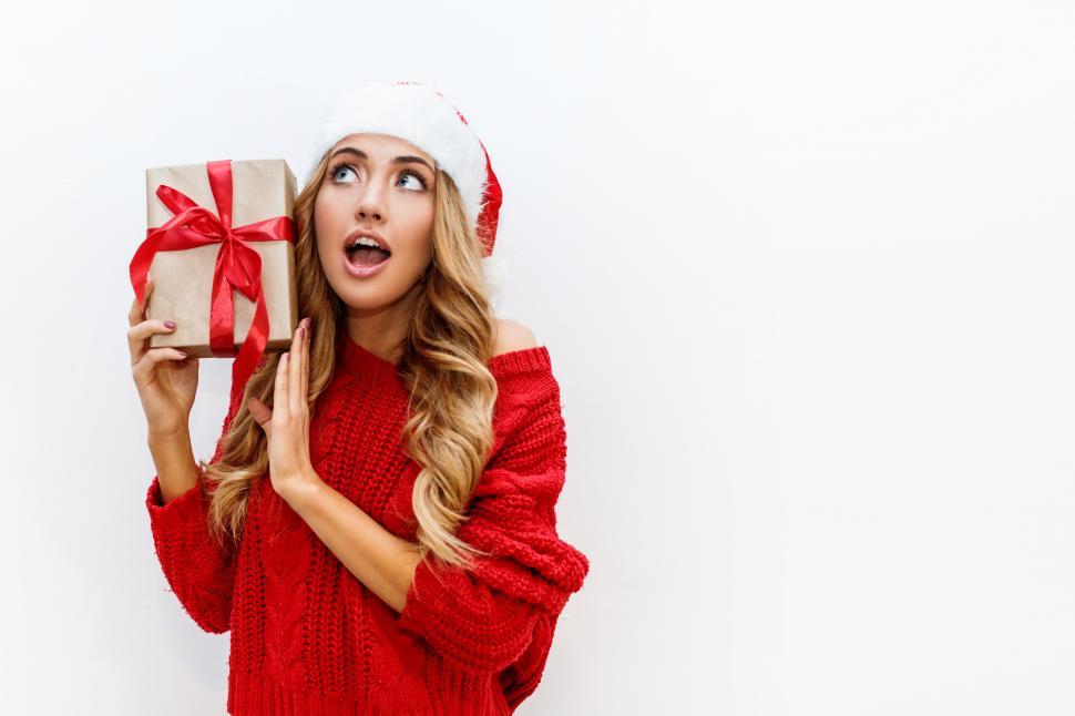 Free Image of Woman in holiday dress mystified by wrapped package 