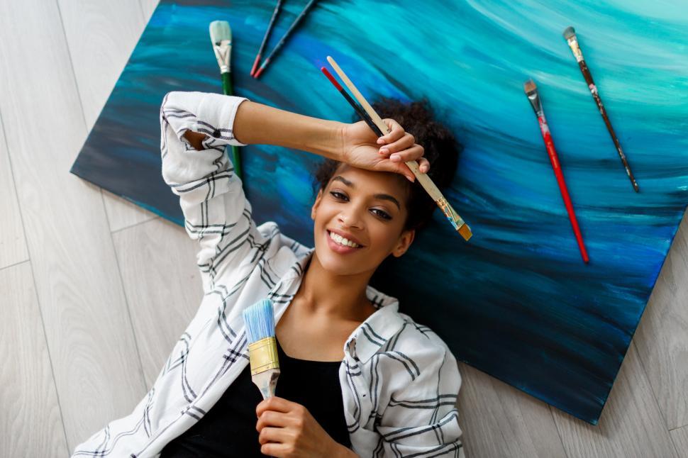 Free Image of Happy painter lying on canvas and looking at the camera 