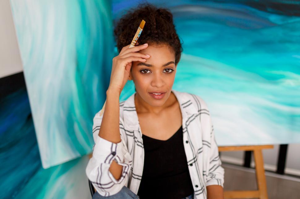 Free Image of Woman posing in her art studio with abstract paintings 