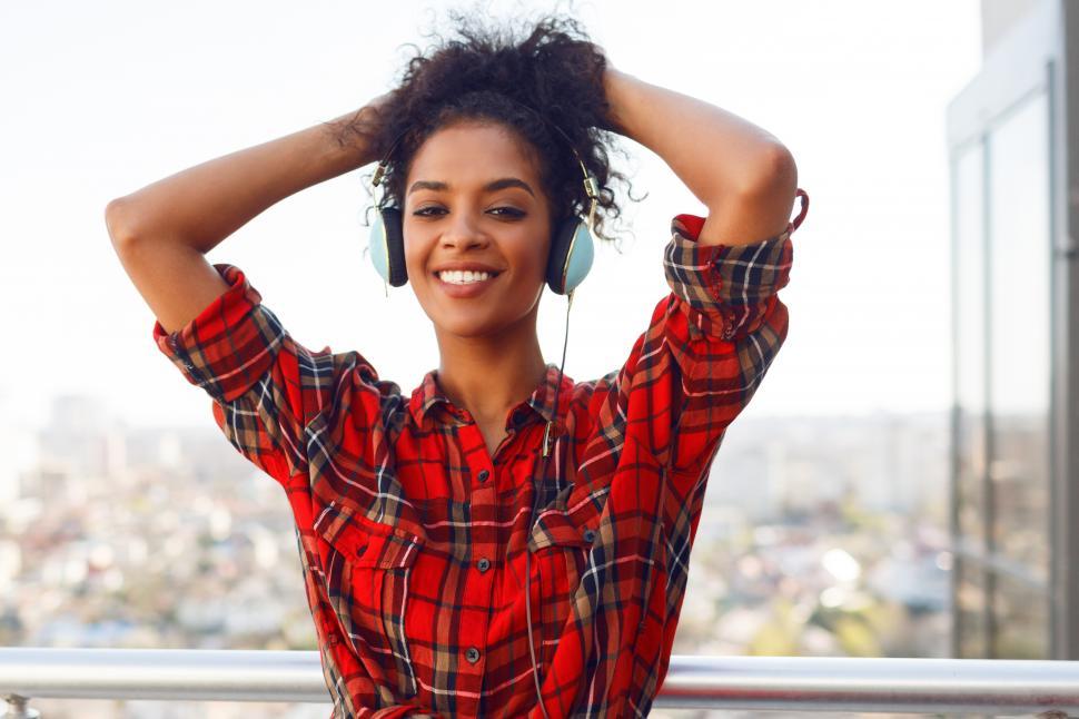 Free Image of Enthusiastic woman posing with earphones on the rooftop 