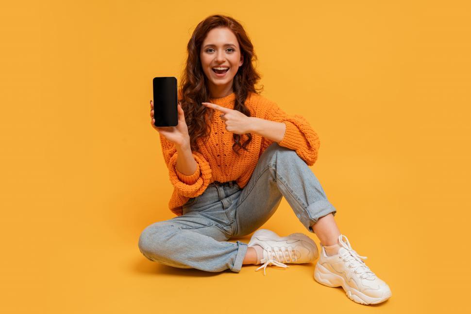 Free Image of Woman showing smartphone screen and pointing at it 