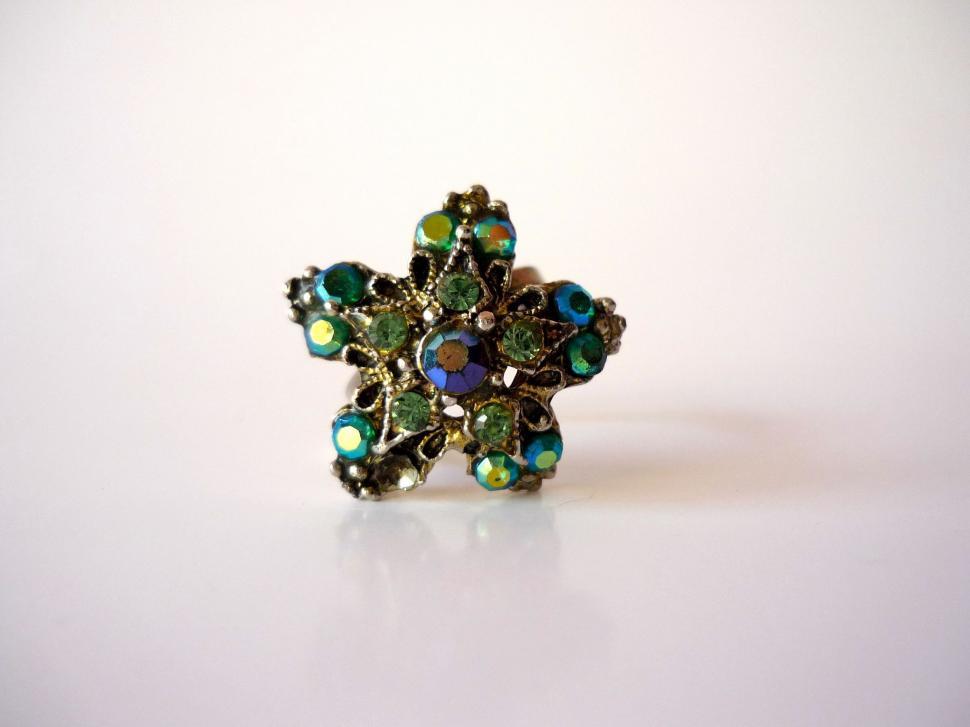 Free Image of Green and Blue Flower Ring on White Surface 