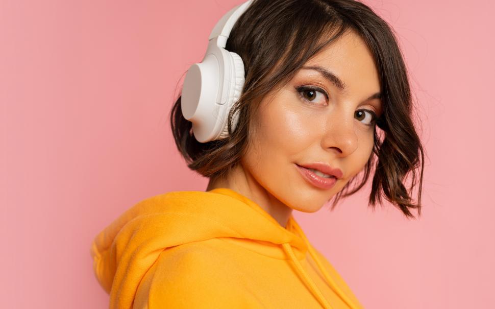 Free Image of Woman listening music by earphones, looking at camera 