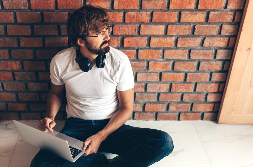 Free Image of Hipster man using laptop and sitting on floor at home 