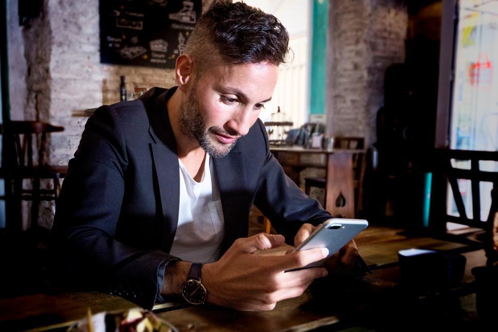 Free Image of an urban young man in a pub using the smartphone 