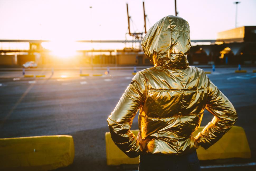 Free Image of an urban girl with a golden jacket in the sunset 