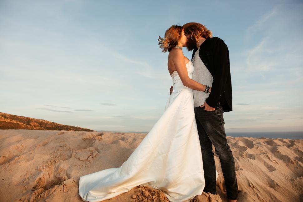 Free Image of a young bride kissing at the beach 