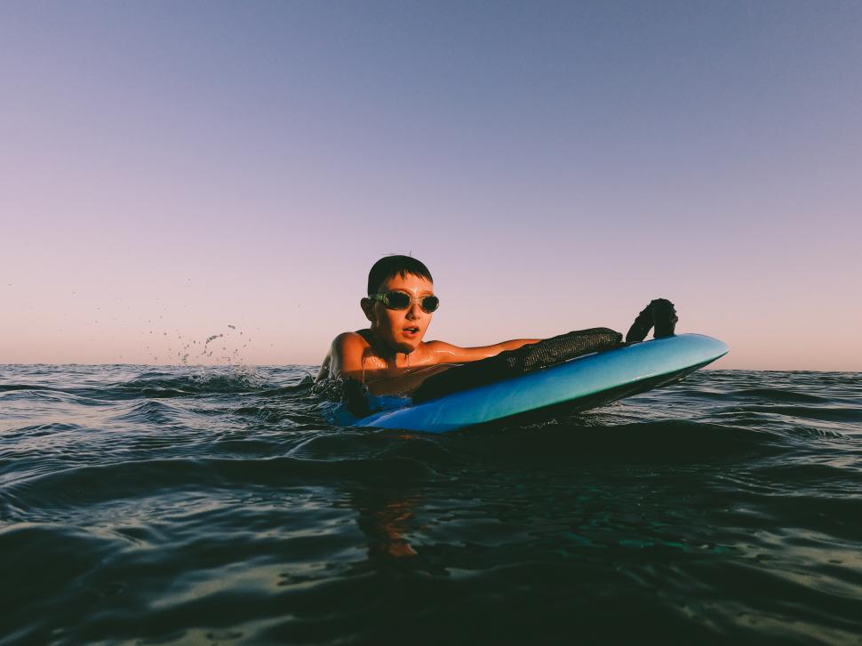 Free Image of a young kid in the ocean with surfboard 