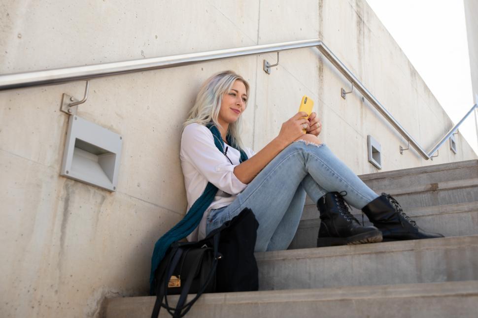 Free Image of a young woman using a smartphone on the steps 