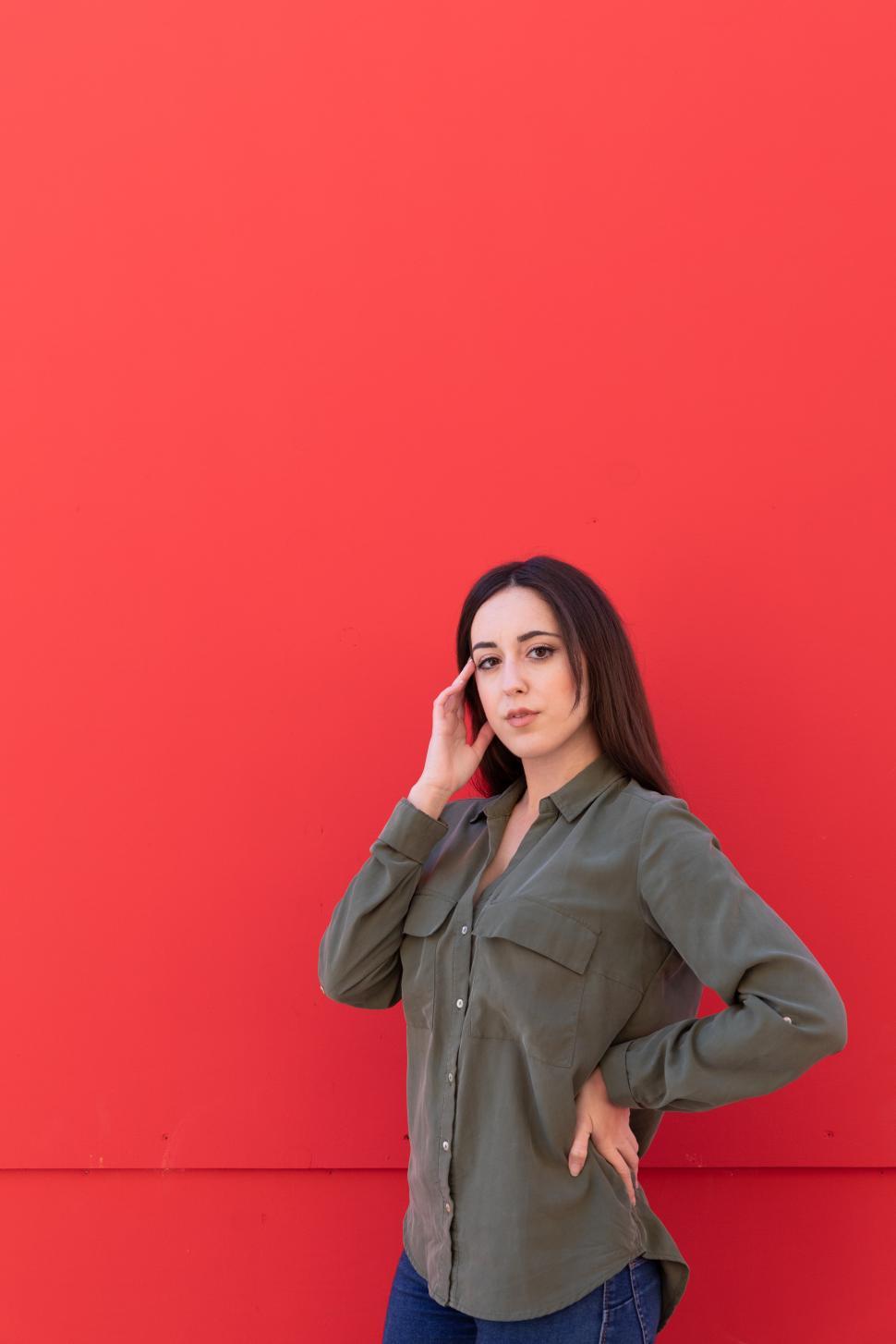 Free Image of Young Brunette woman wearing a casual green shirt on red background 
