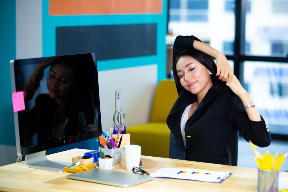 Free Image of Business woman stretching at her desk 