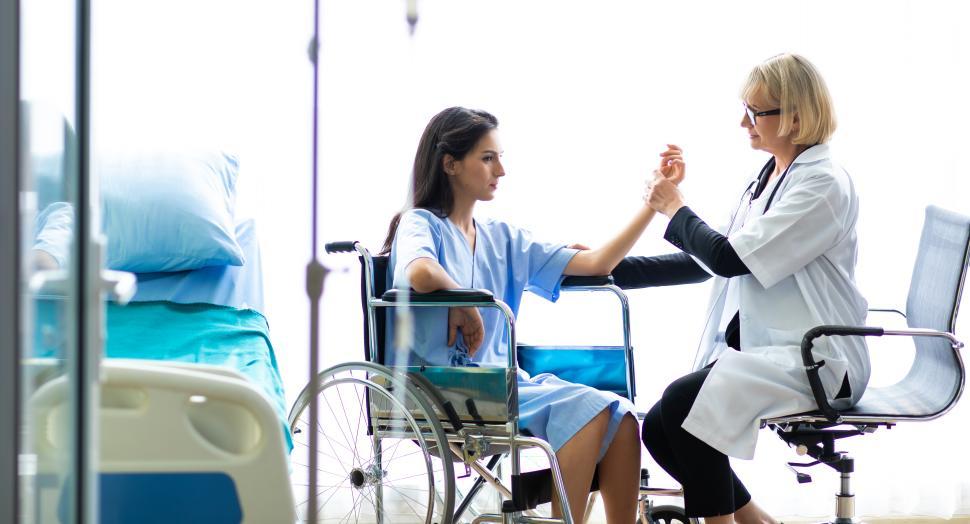 Free Image of Doctor assessing  a woman patient in a wheelchair 