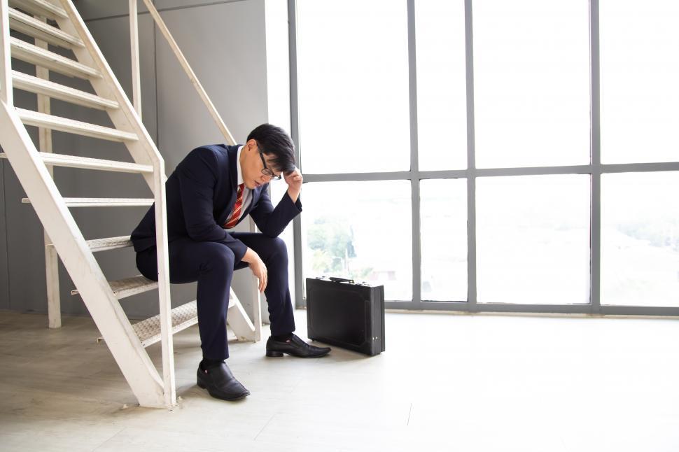 Free Image of Sad businessman sitting on staircase inside the office 
