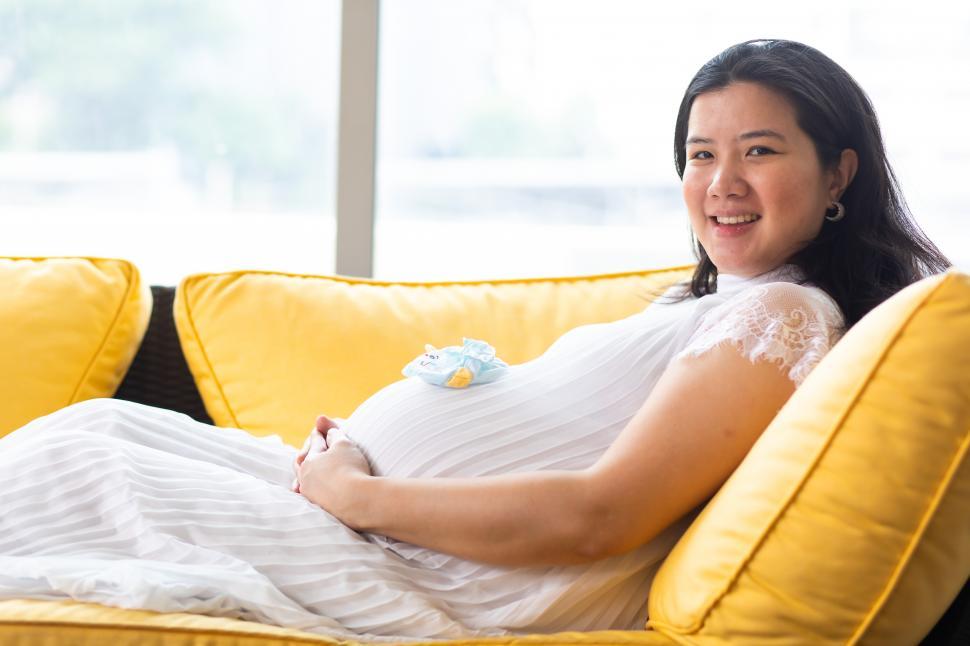 Free Image of Happy pregnant woman sitting on sofa 