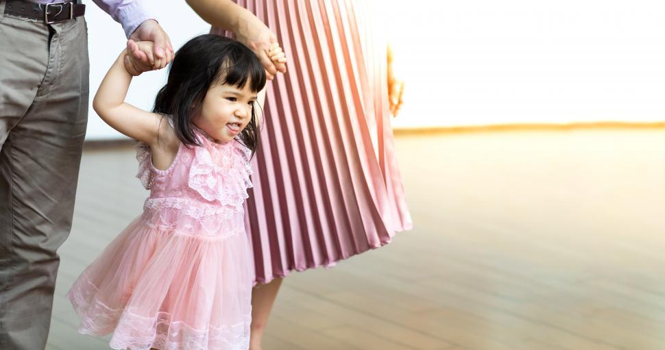 Free Image of Cute toddler in pink dress with parents 