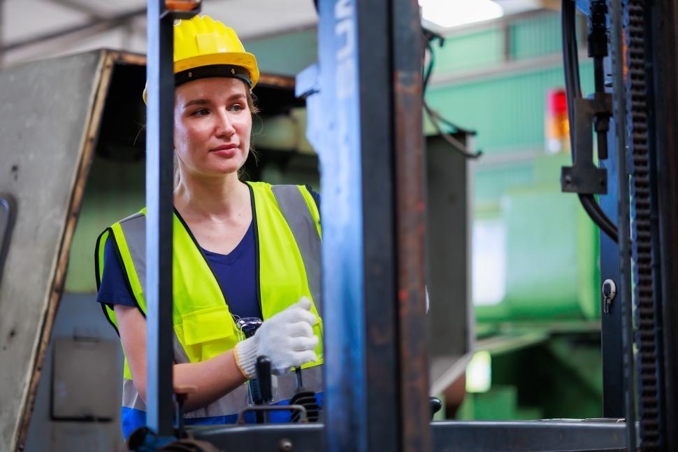 Free Image of Caucasian female warehouse worker driving forklift 