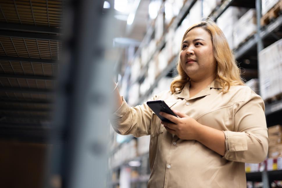 Free Image of Female warehouse worker looks at inventory 