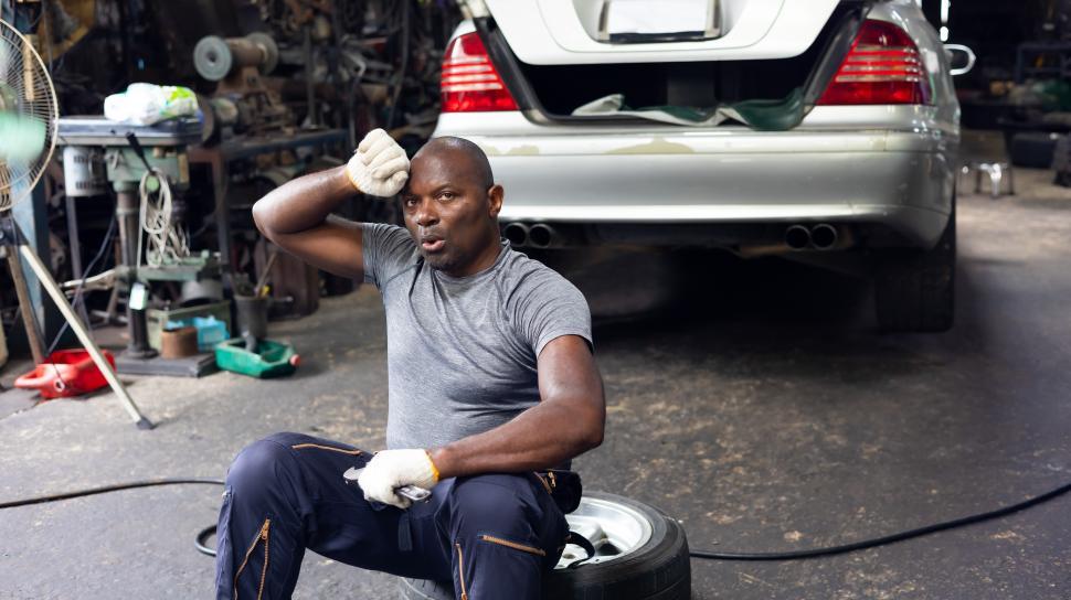Free Image of Tired mechanic wiping sweat in auto shop 