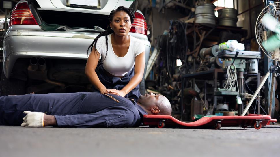 Free Image of Female mechanic doing chest compressions on coworker 