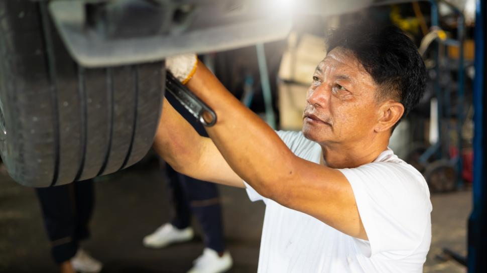 Free Image of Senior asian male mechanic working under car 