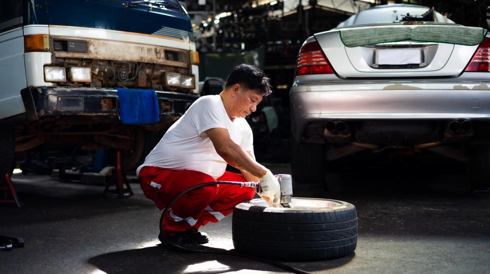 Free Image of Man working on changing a tire 