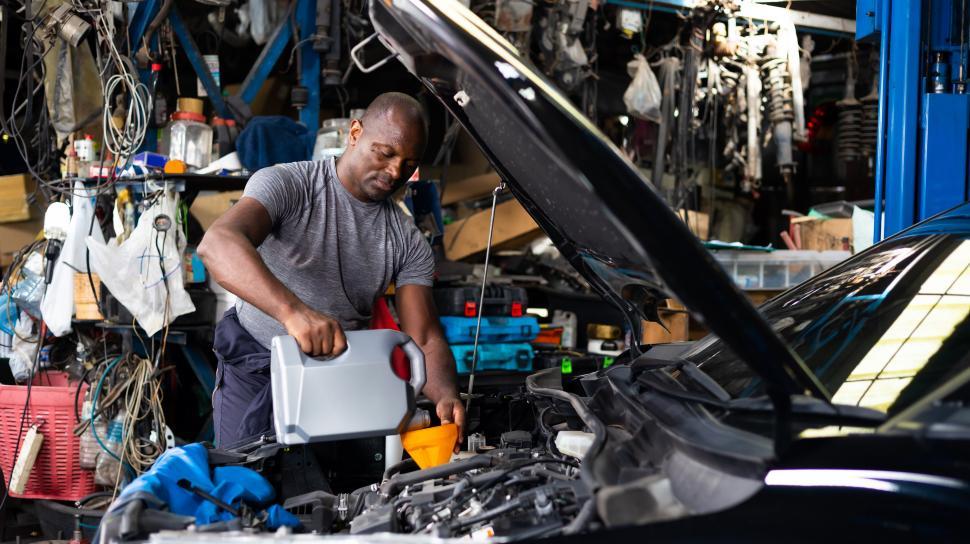 Free Image of Male mechanic pouring oil into car engine 