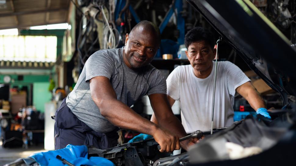 Free Image of Two mechanics work under the hood of a car 