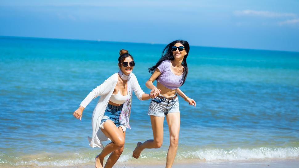 Free Image of Two young women happy running together on the beach. 