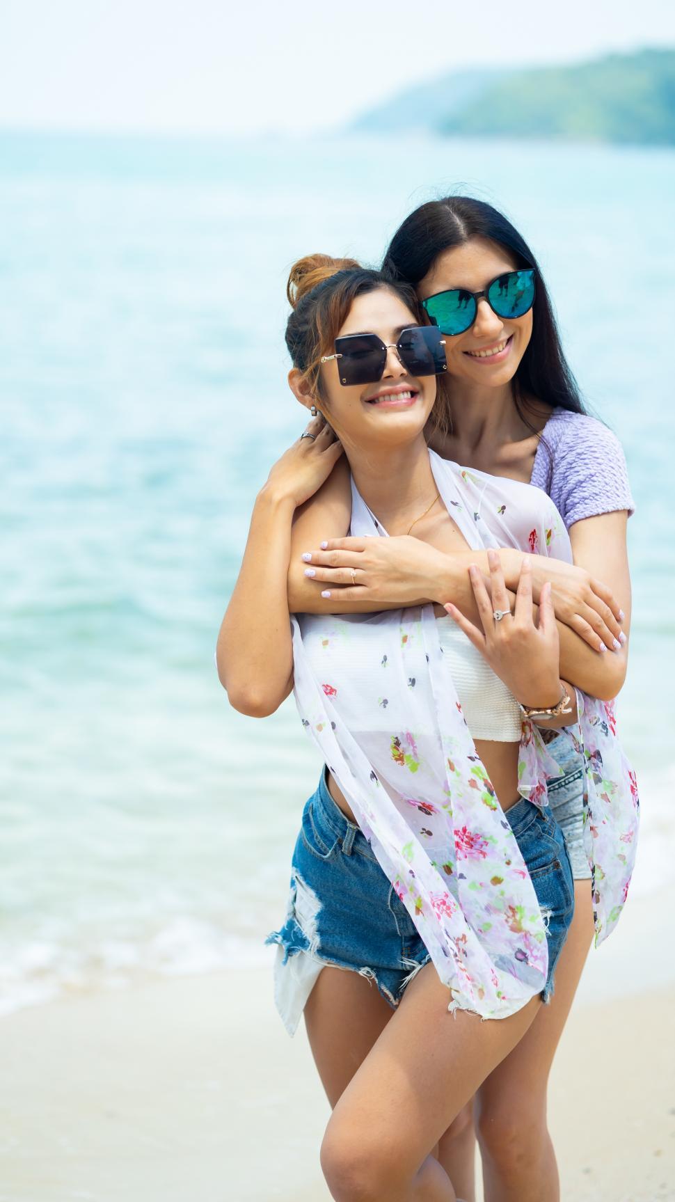 Free Image of Lesbian couple on vacation together, embracing on the beach 