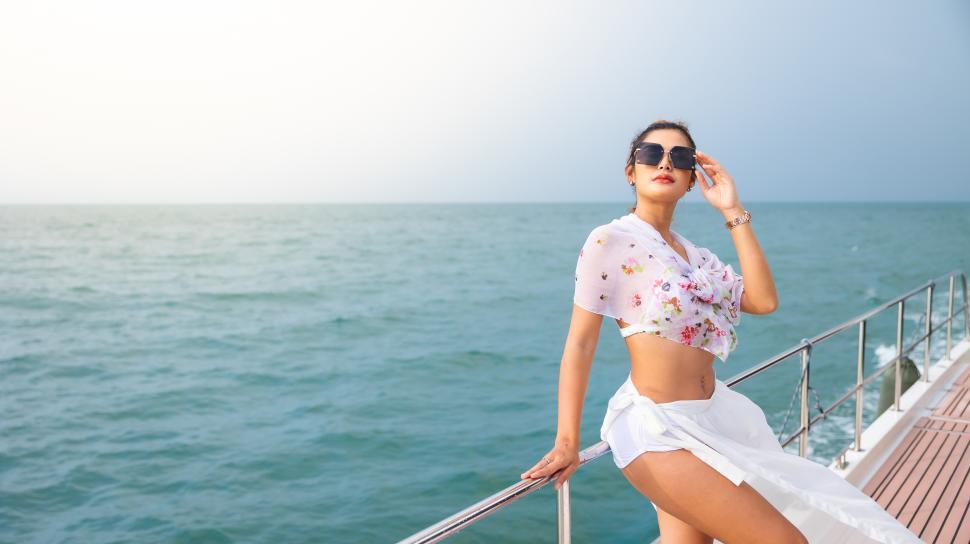Free Image of Woman on a boat, looking glamorous, leaning on a railing 