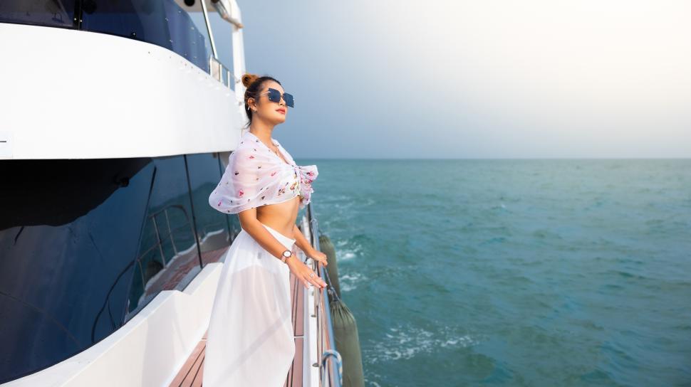 Free Image of Portrait of beautiful Asian woman looking over the ocean from the side of a boat 