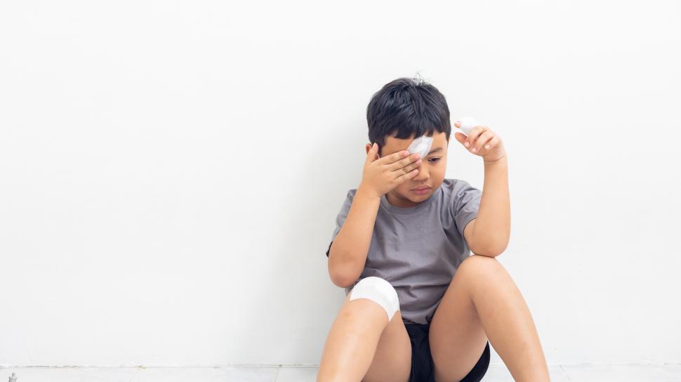 Free Image of Boy is sad and has wound on face knee and fingers 