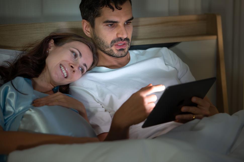 Free Image of Pregnant woman with husband in bedroom interacting with tablet 