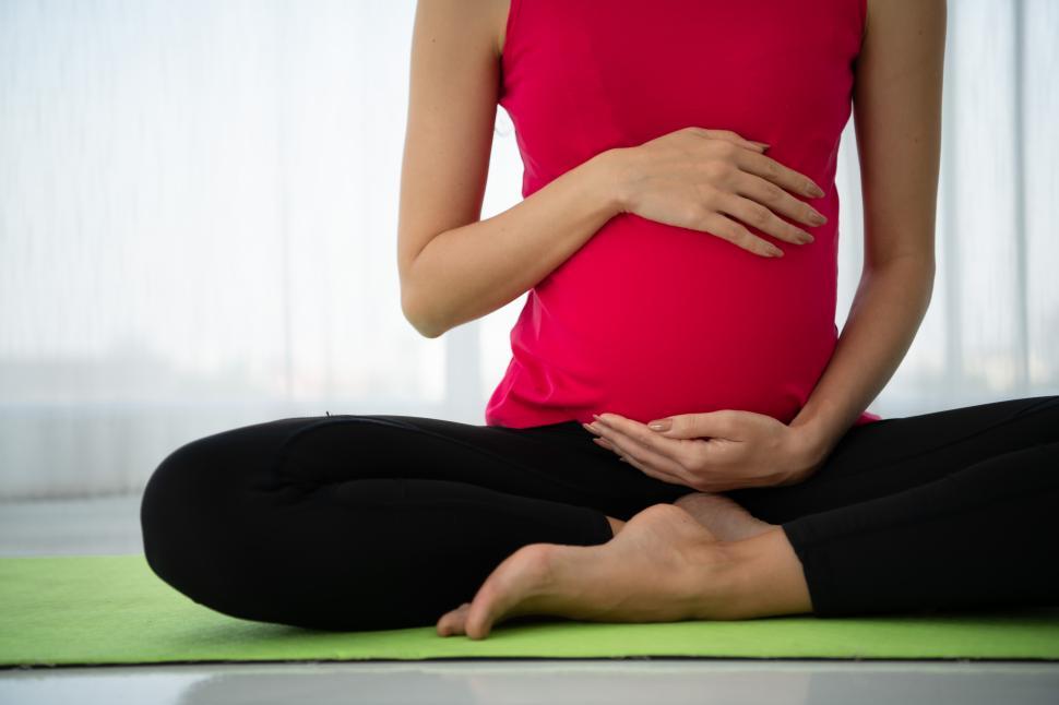 Free Image of Anonymous pregnant woman meditates in a living room. 
