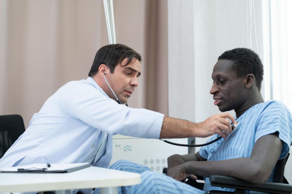 Free Image of Doctor examining the symptoms of a patient in bed 
